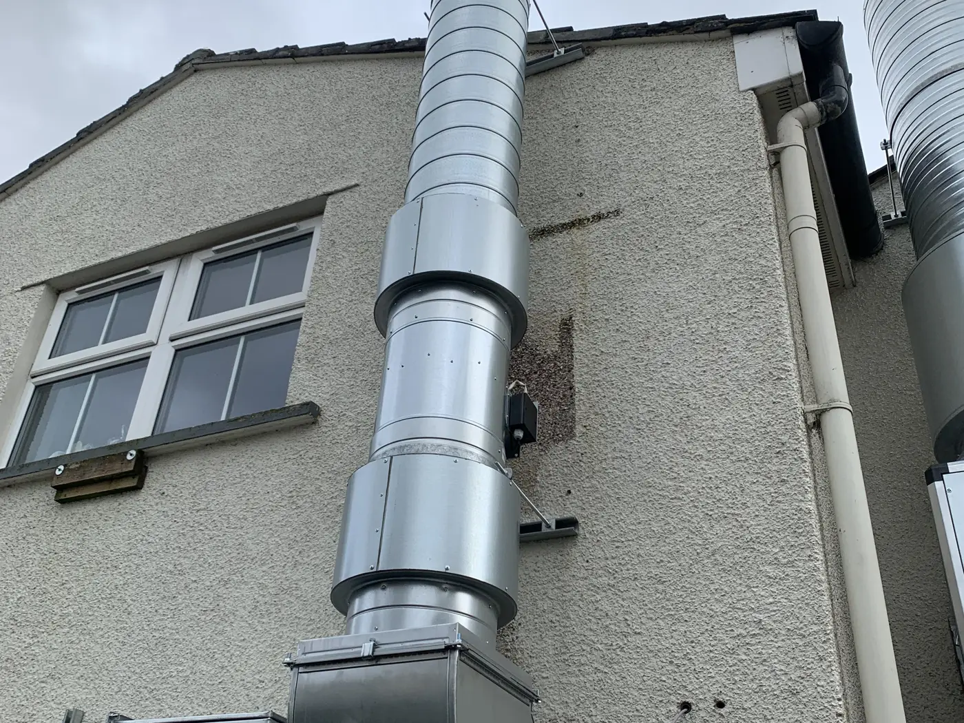 Galvanised external extract duct with in-line fan and attenuators running up the gable wall to discharge above the roof at the George and Dragon, Clifton