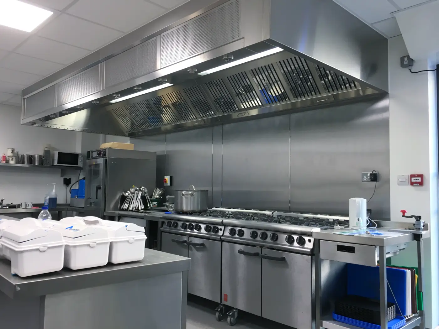 Stainless steel wall canopy with baffle filters and integrated supply air above a commercial gas range